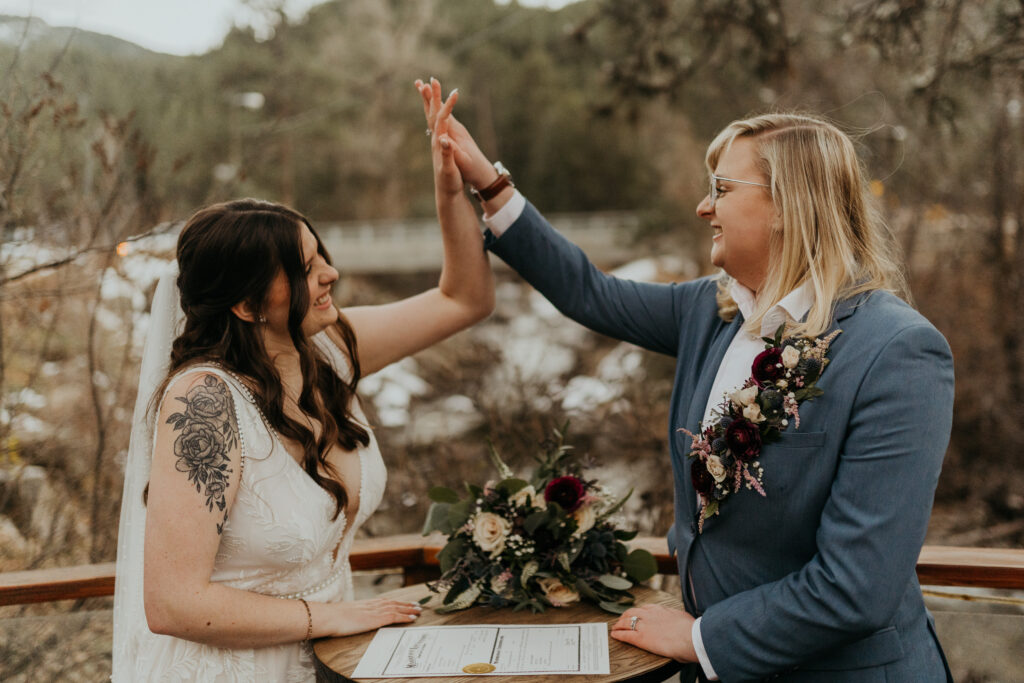 Couple doing a high five after signing their marriage license overlooking boulder creek