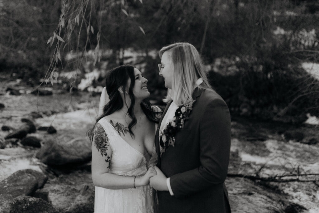 Black and white photo of couple standing next to eachother by Boulder Creek after their wedding at Boulder Creek by Wedgewood Weddings